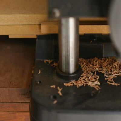 Closeup of electric machine for joinery with stainless steel part and shavings on table in workroom